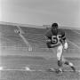 Photograph: [Football player number 66 running sideways through a football field,…