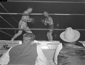 [Two reporters watching a boxing match]