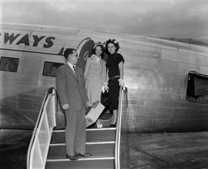 [Two women and a man exiting plane]