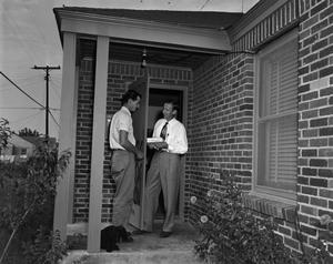 [Two men on porch outside house]
