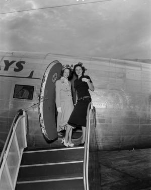 [Two women stand on boarding stairs to airplane]