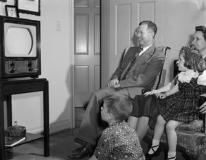 [Man, woman, and two children watching TV]