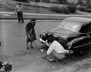 [Woman demonstrates with car jack]