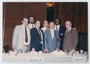 [Group photo of 7 men at a banquet]