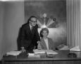 Photograph: [Woman sitting next to a man in office]