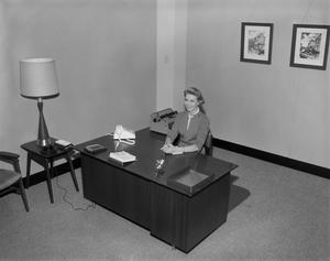 [Woman sitting at a desk]