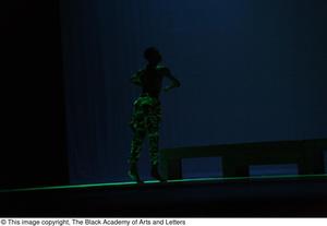 [Photograph of a dancer illuminated by green light]