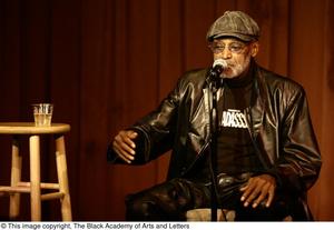 [Photograph of Melvin Van Peebles speaking into a microphone at a film festival]