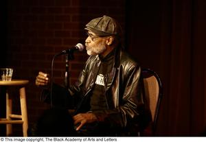[Photograph of Melvin Van Peebles in a chair on stage at a film festival]