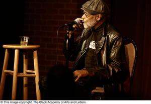 [Photograph of director Melvin Van Peebles giving a talk on stage]