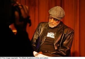 Primary view of object titled '[Photograph of an individual filming Melvin Van Peebles on stage]'.