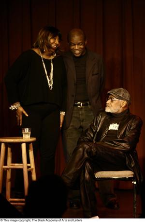 [Photograph of two unidentified individuals standing by Melvin Van Peebles on stage]