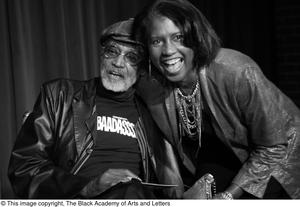 [Photograph of Melvin Van Peebles posing with a woman on stage]
