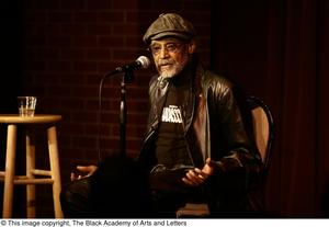 [Photograph of Melvin Van Peebles as he speaks on a stage at a film festival]