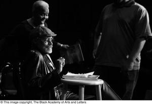 [Photograph of two individuals standing by Melvin Van Peebles on stage]
