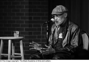 [Photograph of Melvin Van Peebles seated behind a microphone]