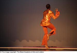 [Photograph of a man in gold dancing with his back to the camera]