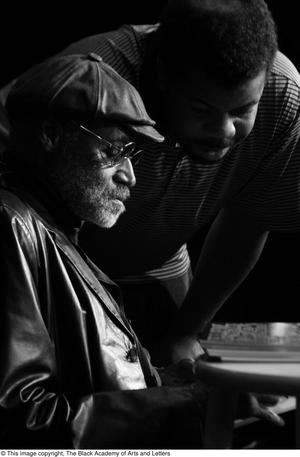 [Photograph of Melvin Van Peebles signing a book for a man]