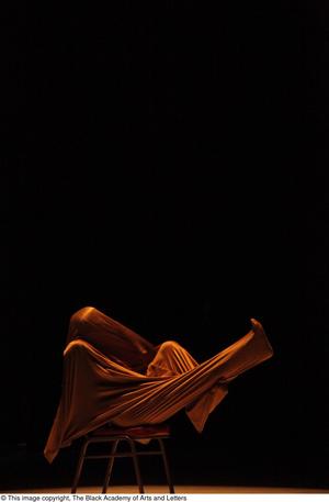 [Photograph of an individual performing a dance wrapped in yellow fabric]