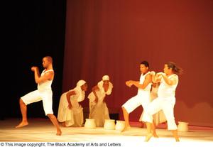 [Photograph of dancers performing on stage in white outfits]