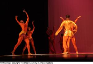[Photograph of many dancers on a stage dressed in gold outfits]