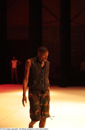 [Photograph of a man standing on stage in camouflage shorts, 2]