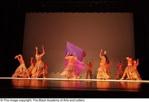 [Photograph of many dancers on stage with a piece of purple fabric]
