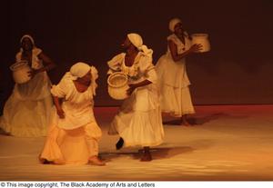 [Photograph of women dancing with baskets on a stage]