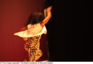 [Photograph of a dancer performing on stage in zebra-print clothing]