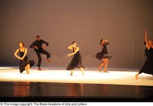 [Photograph of six dancers performing on stage in black outfits]