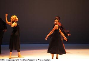 [Photograph of three women dancing on stage in black dresses]
