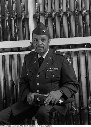 [Col. Joe D. Sasser posing in front of drill rifles, 2]