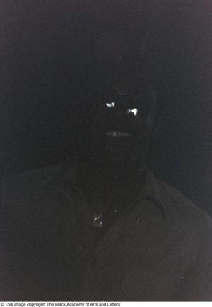 [Underexposed photograph of an individual wearing sunglasses]