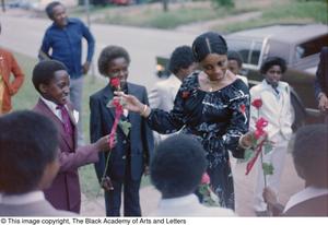 [Photograph of woman receiving two roses from young boys]