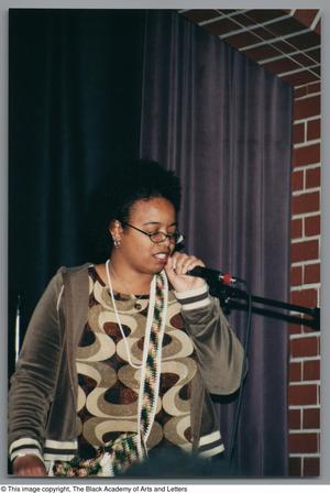 [Photograph of a woman, with her eyes closed, holding a microphone in her left hand]