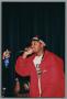Primary view of [Photograph of a man rapping into a microphone and staring into the crowd]
