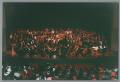 Photograph: [Photograph of an orchestra ensemble and choir on a stage]