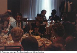 [Photograph of various groups of people, sitting at different dining tables]