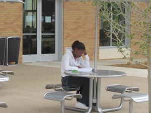 [Student at table outside of Business Leadership Building]