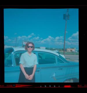 [Photograph of a woman standing outside a blue automobile]