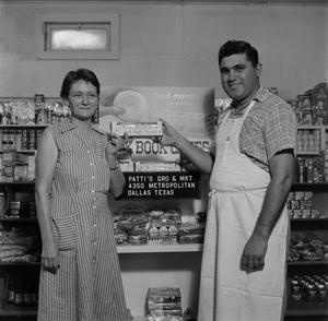 [Man and woman holding donuts in front of display 1 of 2]