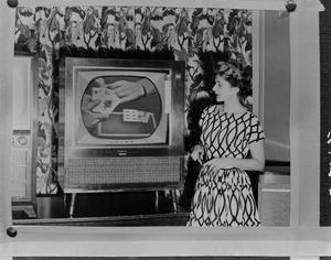 Primary view of object titled '[Marie Stevenson next to a television screen]'.