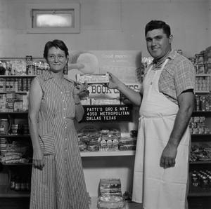[Man and woman holding donuts in front of display 2 of 2]