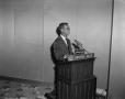 Photograph: [Man with microphone at podium]