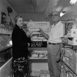 [Man and woman holding donuts in front of store display 1 of 2]