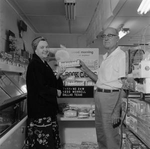 [Man and woman holding donuts in front of store display 2 of 2]