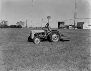 [Man on tractor in grass field]