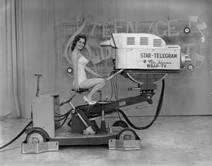 [Woman in a swimsuit sitting on a camera dolly]