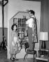 Photograph: [Melvin Dacus and a woman hanging curtains]