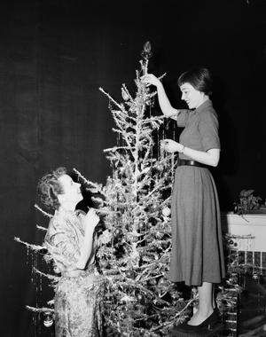 [Photograph of Ann Alden and guest by Christmas tree]